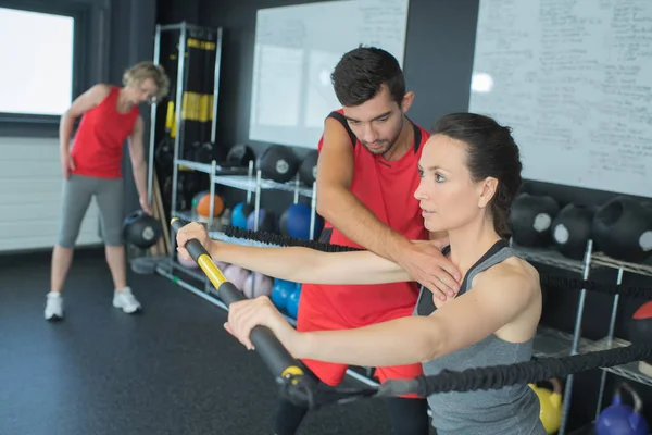 Femme faisant des exercices dans la salle de gym avec l'aide d'un entraîneur personnel — Photo