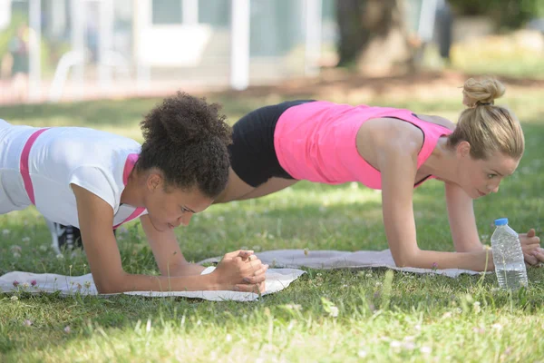 Passar unga kvinnor gör plankan ställning outdoorss — Stockfoto