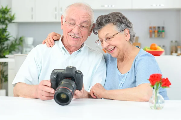 Älteres Ehepaar betrachtet Fotos auf dem Display einer Digitalkamera — Stockfoto