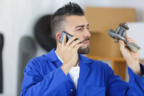 Mekaniker som håller en del anropande fabriken på telefonen — Stockfoto