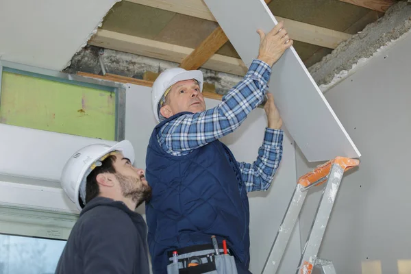 Trabalhadores da construção ajustando painéis de teto — Fotografia de Stock