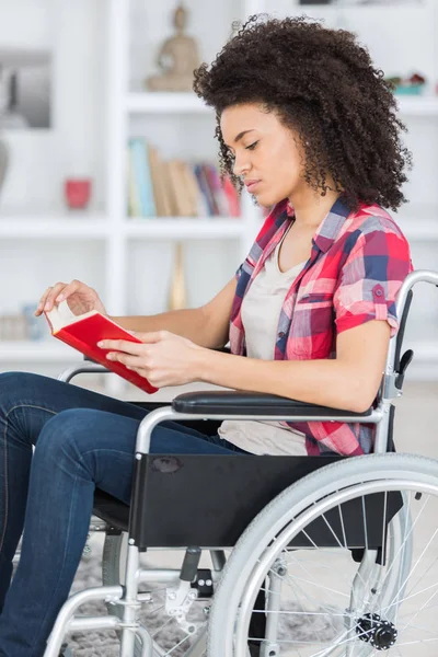 Mulher na cadeira de rodas lendo um livro — Fotografia de Stock
