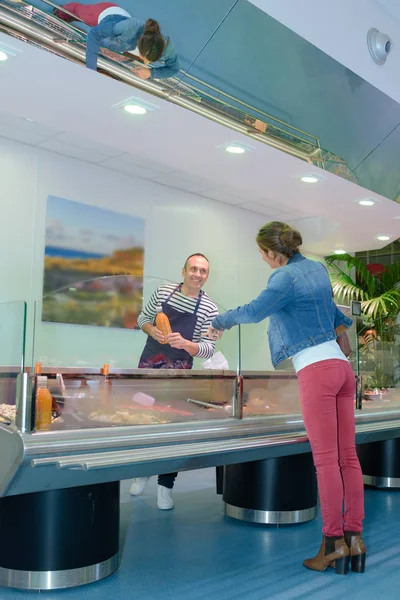 Jonge vrouwelijke klant kopen van vis in winkel — Stockfoto