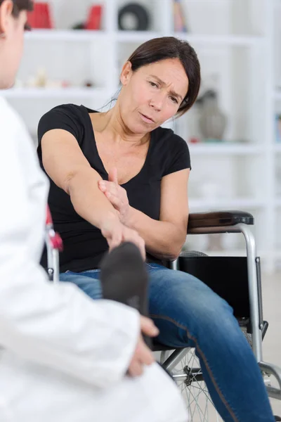 Пациентка жалуется на свою руку в медицинском кабинете — стоковое фото