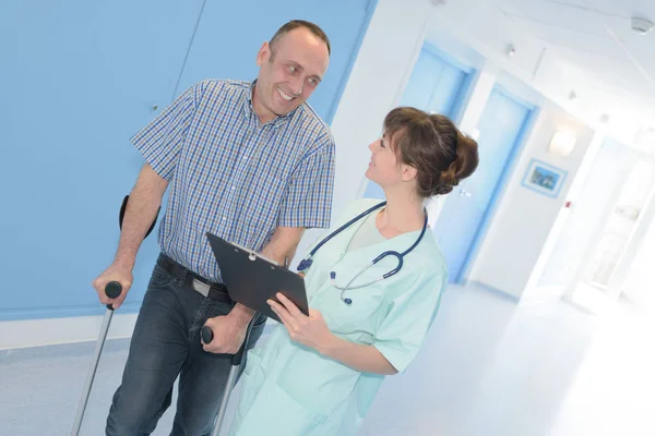 Verpleegkundige man helpen met krukken in een ziekenhuis — Stockfoto