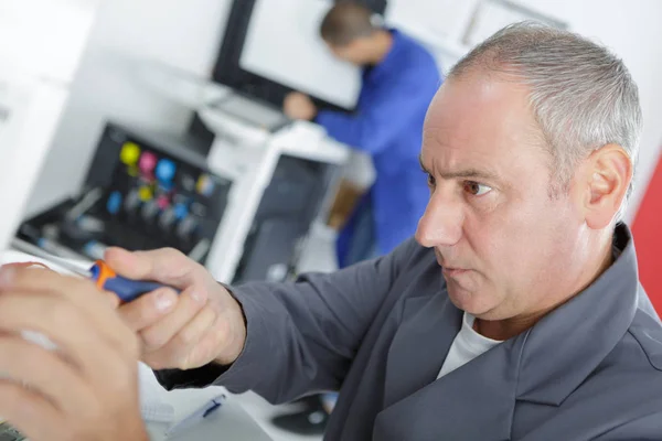 Mogna manlig tekniker kontrollerar kylskåp med digital multimeter hemma — Stockfoto