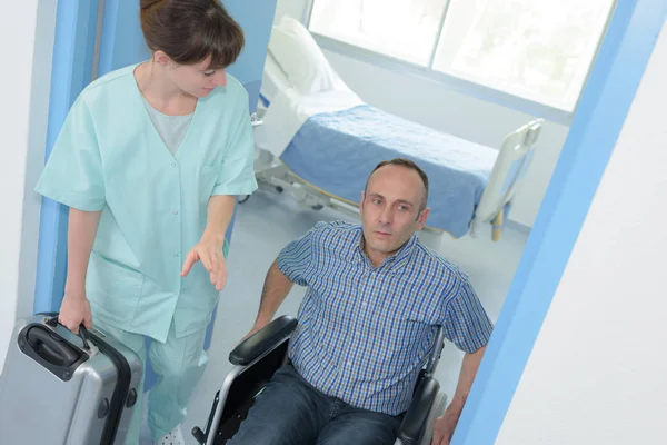 Krankenschwester hilft einem behinderten Mann im Rollstuhl — Stockfoto