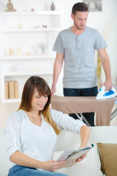 Young couple at home man ironing to relieve his wife — Stock Photo, Image