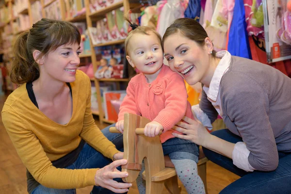 Anne ve kızı oyuncak deposunda çekici satıcı ile — Stok fotoğraf