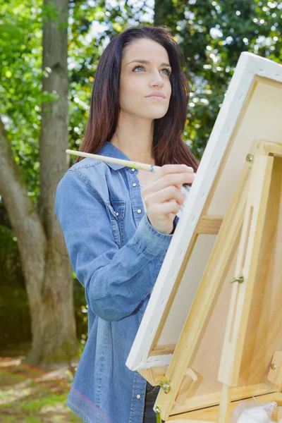 Young female artist painting picture in park — Stock Photo, Image