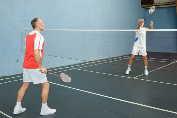 Män som spelar spelet badminton på en domstol — Stockfoto