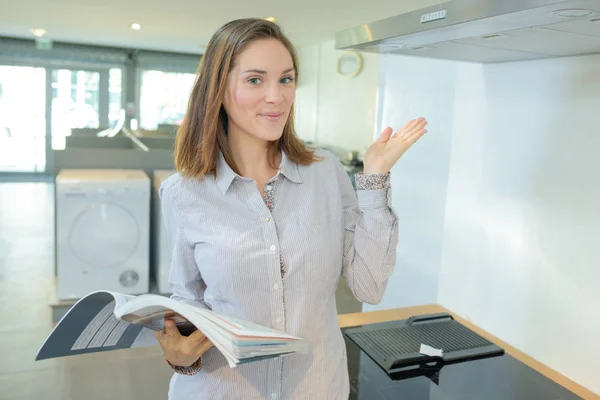 Vrouw houden instructie boek en presenteert nieuwe fornuis — Stockfoto