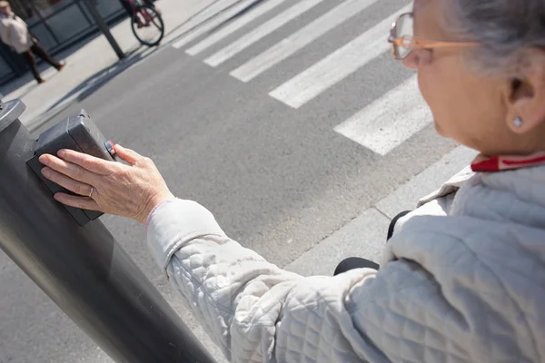 Bejaarde vrouw crosswalk knop in te drukken — Stockfoto