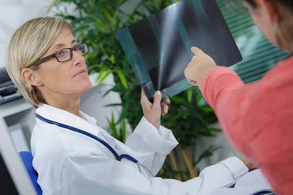 Жінка-лікар пояснює результат обстеження її пацієнта — стокове фото