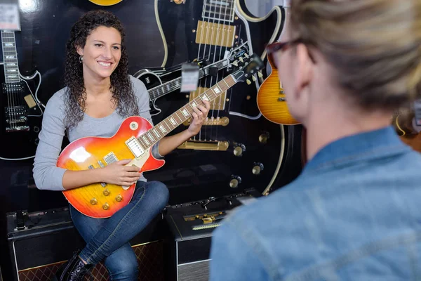 Mladá žena prodávající hraje na kytaru v obchodě — Stock fotografie