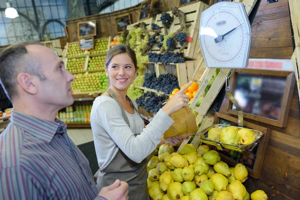 Winkelbediende met een gewicht van kweepeer fruit voor de klant — Stockfoto