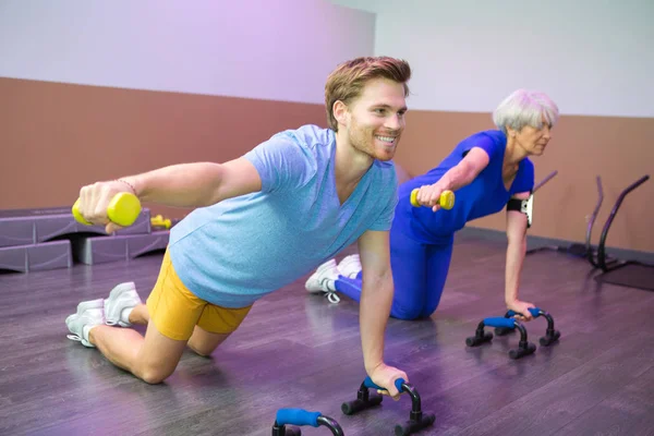 Treinador demonstrando a mulher idosa fazendo fitness — Fotografia de Stock