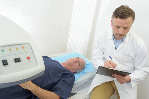 Врач проверяет медицинскую карту пациента во время сканирования — стоковое фото