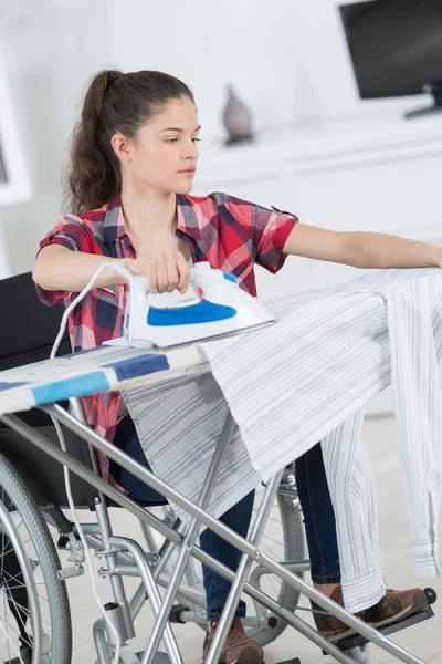 Młoda kobieta niepełnosprawnych jest prasowania w domu — Zdjęcie stockowe