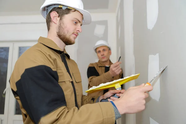 Hombres aplicando relleno en la pared —  Fotos de Stock