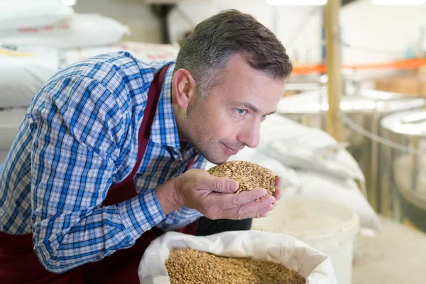 Een knappe jonge barista man glimlachend en houden van koffiebonen — Stockfoto