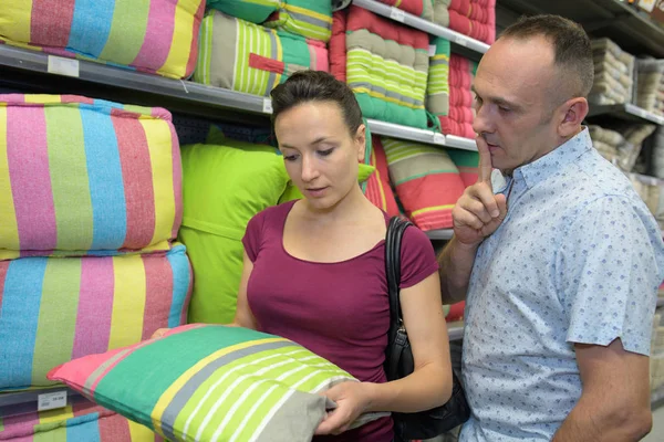 Casal comprando travesseiro fofo na loja têxtil em casa — Fotografia de Stock