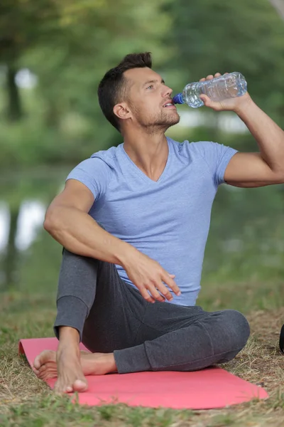 Beau homme buvant de l'eau dans un parc d'été — Photo