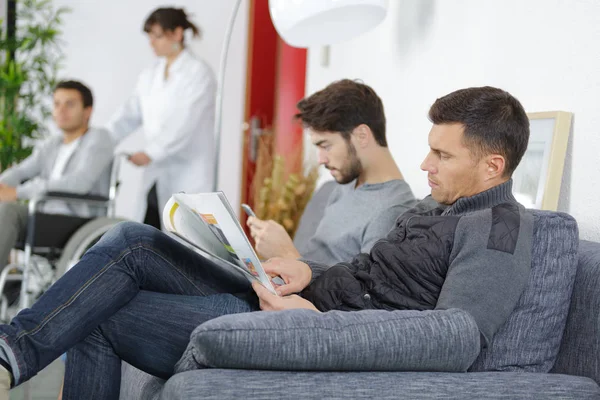 Diferentes personas sentadas en una sala de espera de un hospital — Foto de Stock
