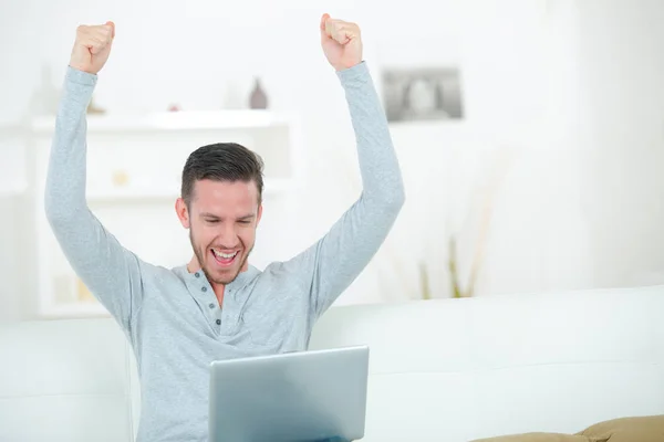 Uomo utilizzando il computer portatile facendo gesto trionfante — Foto Stock