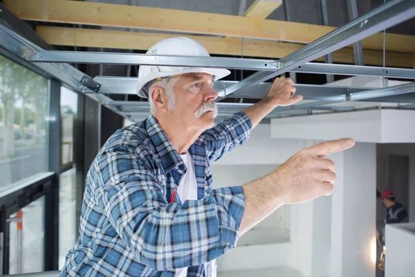 Uomo anziano che lavora su pannelli per soffitti — Foto Stock