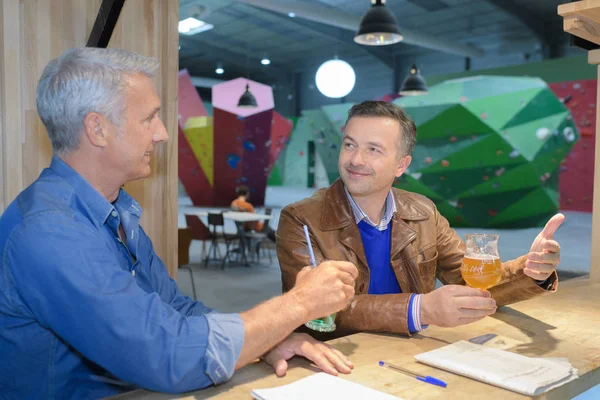 Два зрелых человека сидят в баре скалолазания с пивом — стоковое фото
