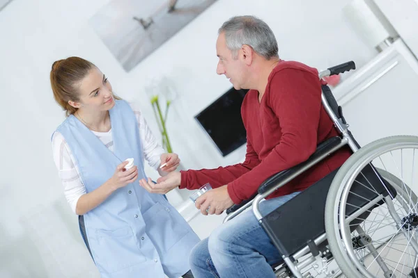 Starszy człowiek na wózku inwalidzkim i jego pielęgniarka — Zdjęcie stockowe