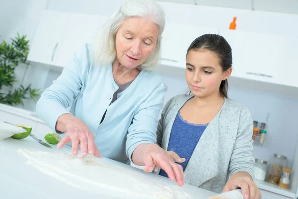 Joven chica haciendo un pastel con su niñera — Foto de Stock