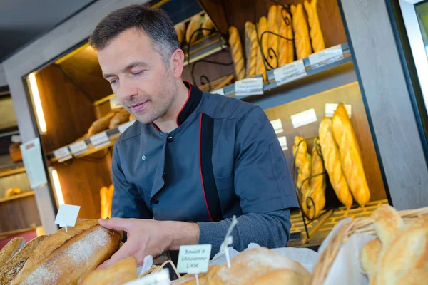 Lojista padaria está orgulhoso de sua produção de pão — Fotografia de Stock