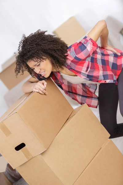 Frau mit Rückenschmerzen trägt schwere Kiste — Stockfoto