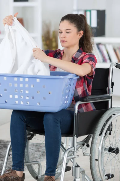 Woman in wheelchair doing a laundry — Stock Photo, Image