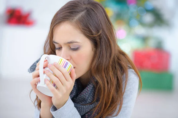 Gelukkig jonge vrouw thee drinken terwijl u ontspant thuis — Stockfoto