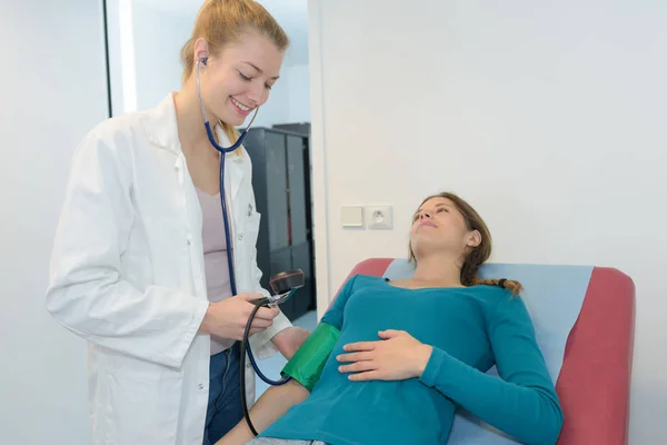 Медсестра проверяет кровяное давление беременной женщины — стоковое фото