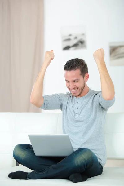 在笔记本电脑前有一个获胜的手势的男人 — 图库照片
