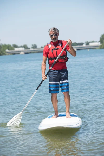 Człowiek cieszyć jazdą na jeziorze z paddleboard — Zdjęcie stockowe