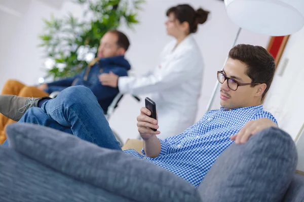Mannen händerna håller smarta telefonen i sjukhuset väntrum — Stockfoto