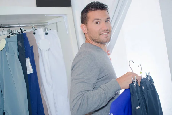 Hombre entrando en vestuario con selección de ropa —  Fotos de Stock