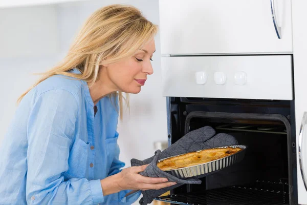 Krásné blond žena dát koláč v troubě na pečení — Stock fotografie