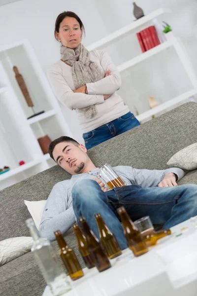 Žena hledá pohrdavě na mladíka uprostřed prázdné lahve od piva — Stock fotografie