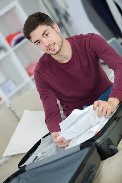 Uomo che prepara la sua valigia grigia in salotto — Foto Stock