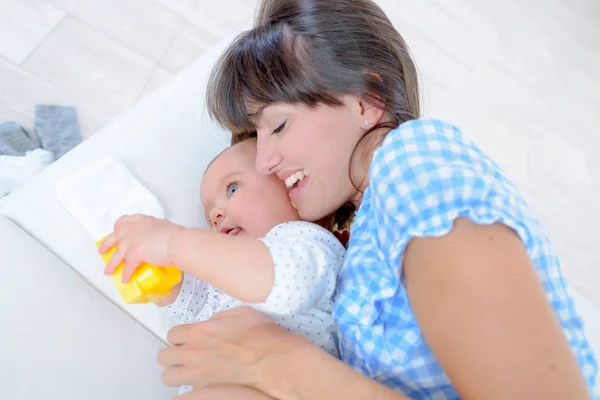 年轻的母亲抱着婴儿在床上 — 图库照片