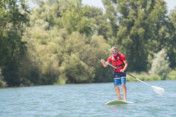 Mature attractive rider contemplating nature sitting on paddle board — Stock Photo, Image