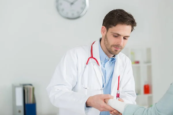 Médico fixando pacientes do sexo feminino tala de pulso — Fotografia de Stock