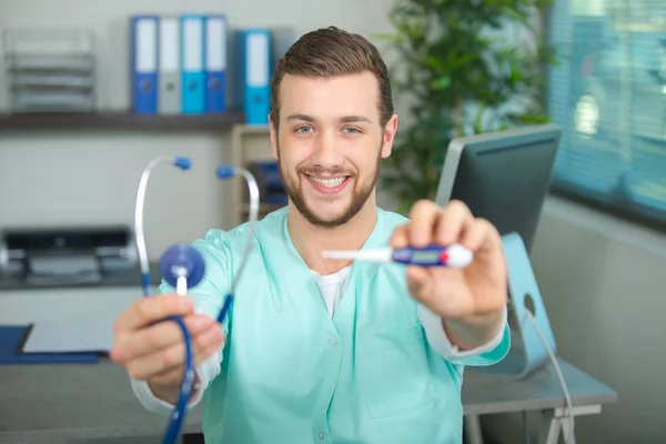 Kinderarzt lächelt und hält Thermometer und Stethoskop in der Hand — Stockfoto