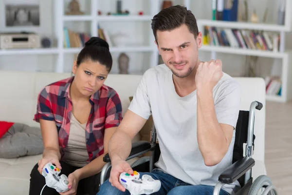 Homem em cadeira de rodas jogando videogames com sua namorada — Fotografia de Stock